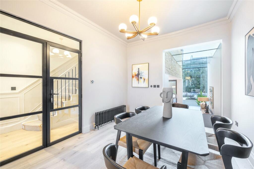 Dining room with black steel-framed glazed doors in a London home renovation