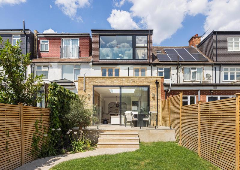 Terraced home with full-width glazed loft dormer and brick rear extension opening onto a stone terrace, West Hampstead, London